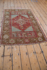 Distressed cherry red and mint green corner of Anatolian rug, showing bronze floral border.