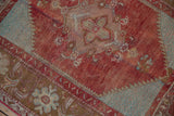Distressed cherry red pile revealing turquoise spandrel, serrated edges, and floral motifs.