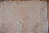 Distressed vintage Oushak rug with pale mauve and ivory even wear, visible foundation.