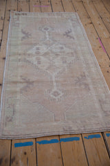 Vintage distressed Oushak runner with worn pile, faded stepped medallion, and soft hues.