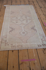 Distressed vintage Oushak runner's corner, showing stepped motifs, dusty mauve, ivory, and intact selvage.