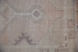 Distressed texture of a vintage Oushak runner, showing pale dusty mauve tones and wear.