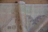 Pile texture of vintage Oushak rug with even wear, faint foundation, and pale mauve stepped pattern.