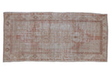 Distressed Turkish Oushak runner with a faded oversized medallion in dusty rose and ivory.