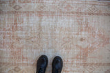 The decorative low pile texture of a distressed Oushak rug with visible wear to the foundation.