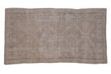 Distressed vintage Oushak rug, faded serrated medallions, geometric border, light neutral hues.