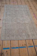 Distressed vintage Oushak rug showcasing faded medallion and geometric border in muted ivory and beige.
