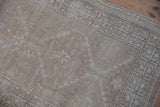 Distressed ivory and beige pile of the vintage Oushak rug, showing geometric border.