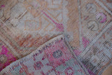 Distressed vintage Oushak rug, showing worn pile, exposed foundation, hot pink, and intact selvage.