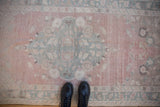 Distressed Oushak rug detail, featuring faded dusty rose and seafoam green motifs.