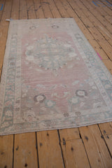 Distressed vintage Oushak rug with abrashed dusty rose pile and muted seafoam green motifs.