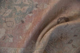 Distressed vintage Oushak rug showing muted dusty rose and seafoam green pile.