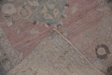 Distressed vintage Oushak rug corner revealing worn dusty rose pile and hand-knotted foundation.