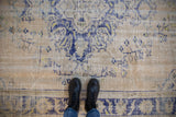 Distressed low pile of a vintage Oushak carpet showing worn cobalt blue and lime green details.
