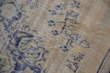Low, worn pile of a distressed Oushak with cobalt blue and pale lime green floral details.
