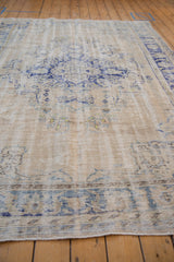 Angled view showing the time-softened, distressed texture on an ivory and blue Oushak carpet.