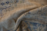A supple drape showing the distressed texture and low pile of a vintage Oushak carpet.