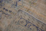 Folded corner of a distressed Oushak rug showing its hand-knotted reverse and low pile.