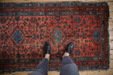 Vintage Lilihan rug with raspberry red field, sapphire blue geometric designs, and feet.