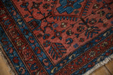 Vintage Lilihan rug corner with raspberry field, sapphire blue boteh border, worn pile, and fringe.