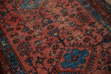 Vintage Lilihan rug's textured pile, showing raspberry red and sapphire blue pinwheel motifs.