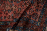Folded vintage Persian Lilihan rug, showcasing raspberry field, sapphire boteh border, and pile wear.