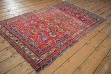 Tomato red and sky blue geometric vines with floral palmettes on a Hamadan rug's tattered border.