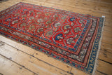 Fringed end of the vintage Hamadan rug, revealing geometric borders in sky blue, sand, and red.