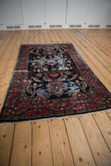 Vintage Lilihan rug's raspberry blossom main border and navy floral field, showing tattered side.
