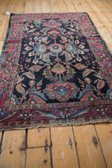 Worn raspberry and navy floral border with distressed fringe of a vintage Lilihan rug.