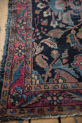 Tattered side and raspberry red floral border detail on a vintage Lilihan rug.