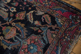 Vintage Lilihan rug's navy field, sprawling red and blue floral cross-sections, and colorful border.