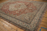 Corner of vintage Sparta rug with distressed madder rust and sand floral field, dark teal border.