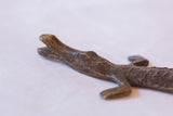 Close-up of the rustic, hand-cast texture on a vintage African bronze crocodile sculpture.
