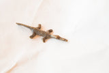 Vintage African bronze lizard casting, highlighting its unique textured form.