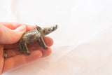 A small vintage African bronze boar figurine showing detailed texture along its back and aged patina.