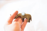 Hand holding vintage African bronze elephant, showcasing its aged patina and handmade charm.
