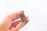 The rustic, ribbed texture and small hanging loop of a vintage bronze bell.