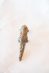The textured, scaly back and long, tapering tail of a vintage bronze pangolin sculpture.