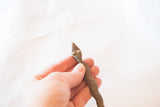 Detailed view of the sculpted head with raised eyes on the vintage bronze snake.