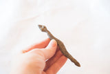 Vintage African bronze snake held in hand to show its scale and textured surface.