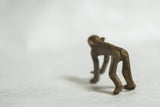 Hand-sculpted back and hind legs of a vintage bronze monkey figure with a textured patina.