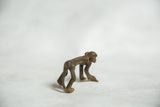 Vintage bronze monkey sculpture viewed from behind, showing its arched back and textured spine.