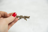 Handmade bronze crocodile pendant held to show its small scale and textured body.