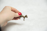 Vintage African ram pendant held in hand, demonstrating its small scale and bronze patina.