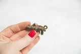 Small vintage boar pendant showing its handmade texture and dark bronze patina.