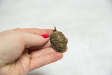 Vintage African bronze face pendant held to show scale and detailed handmade texture.