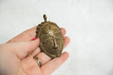 Intricate vintage African head pendant showing its dark bronze patina.