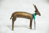 Bronze antelope sculpture with spiral horns and patina, displayed with a marker for scale.