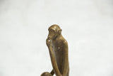 Profile view of a vintage bronze monkey sculpture in a thoughtful, hand-to-chin pose.